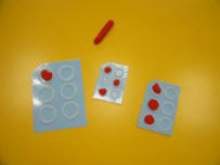 Ms objetos que simulan el cajetn braille: seis crculos sobre un papel o cartn que se rellenan con plastilina.